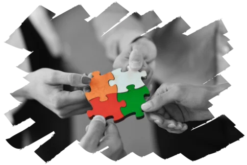 Vier Hände fügen farbige Puzzleteile zusammen – Symbol für Teamarbeit, Coaching & Verbindung